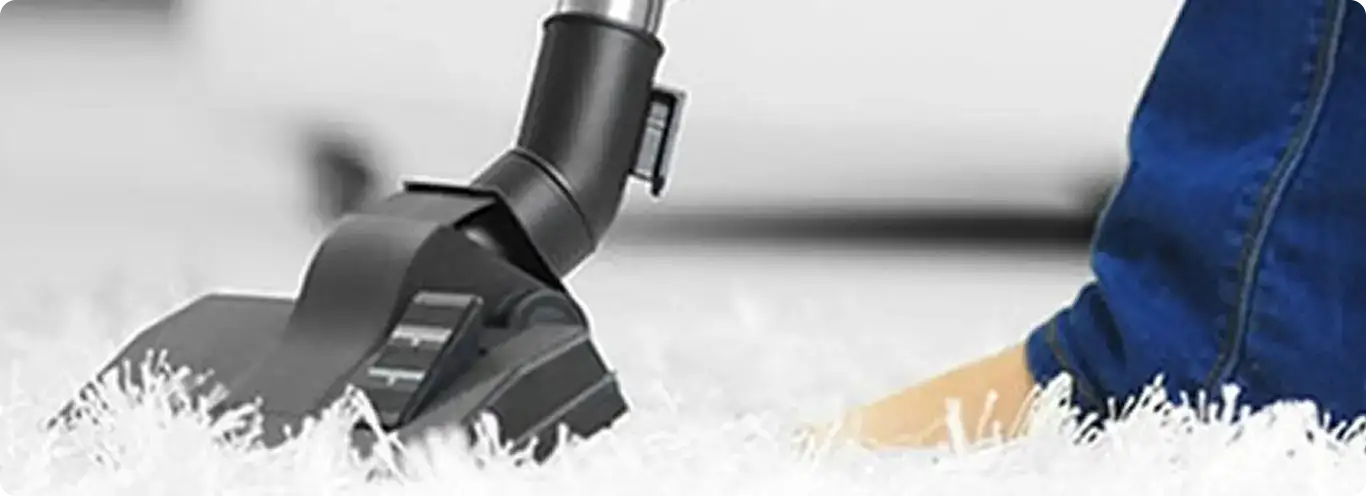 Close-up of a professional vacuuming a white carpet in Granger.